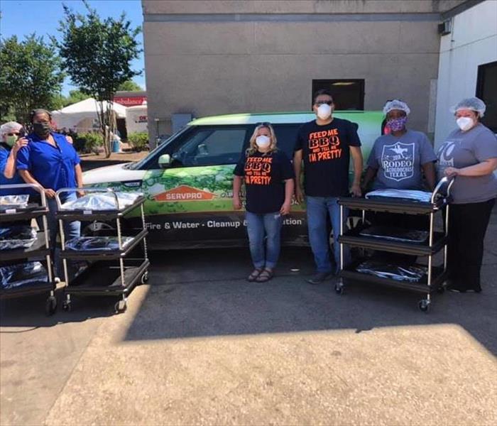 A group of people standing around a SERVPRO vehicle.