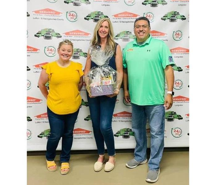 SERVPRO Employees giving woman a gift basket
