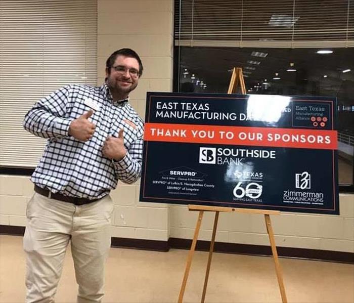 A man standing in front of a sign for an event