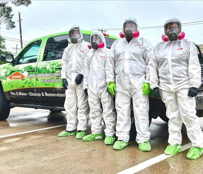 SERVPRO employees wearing TYVEK suits in front of a SERVPRO vehicle.